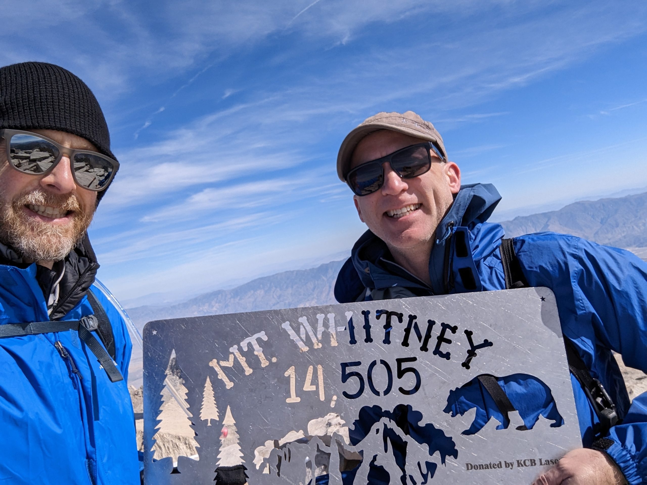 Vaughn and Mat standing on the summit of Mt. Whitney holding a metal sign denoting the elevation of 14,505 feet.