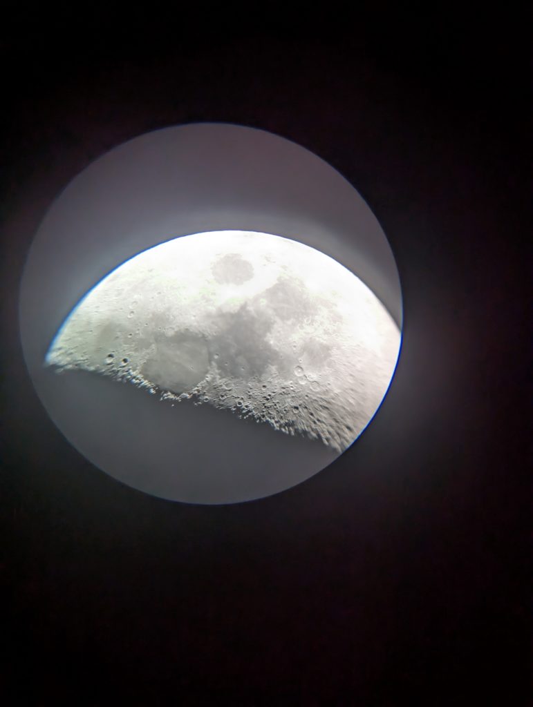 Half moon through a telescope. You can see the terminator and make out multiple craters. But bad fire holding the phone up against the eye piece.