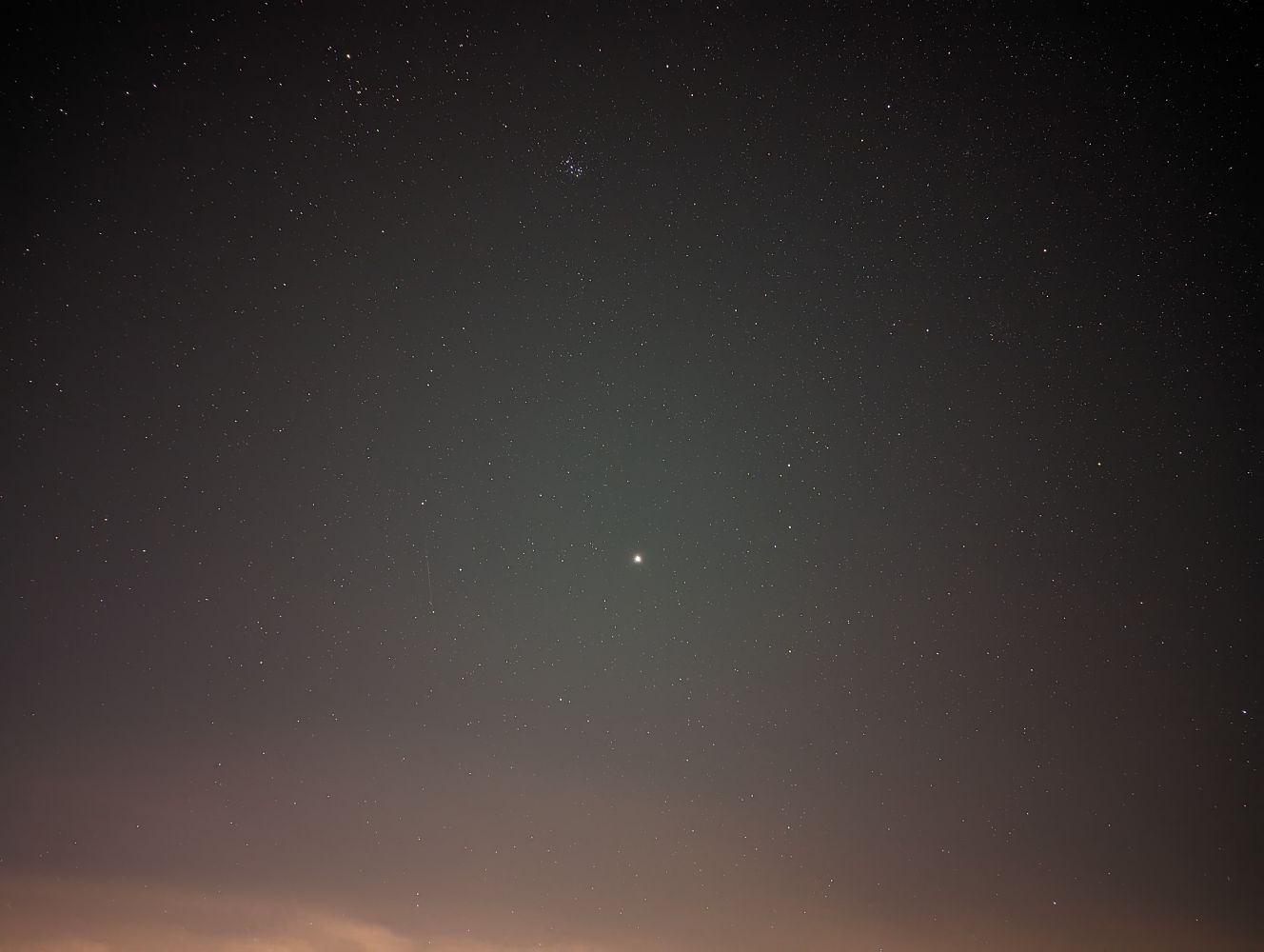 A clear night sky taken in astrophotography mode. Thousands of stars around a bright Jupiter. There is a faint streak to the left of Jupiter which is the only Geminid meteor I caught in an image.