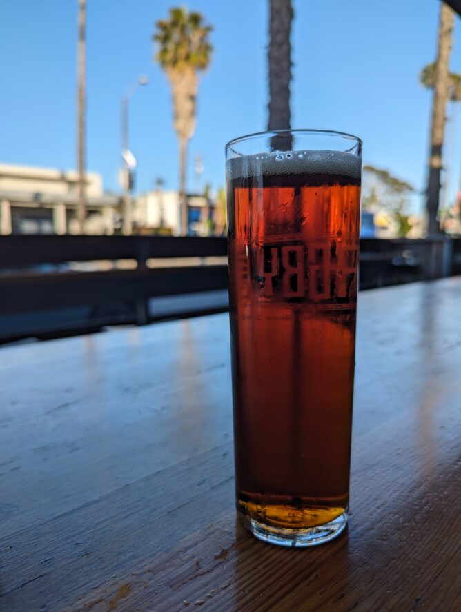 A tall, skinny glass of amber colored beer