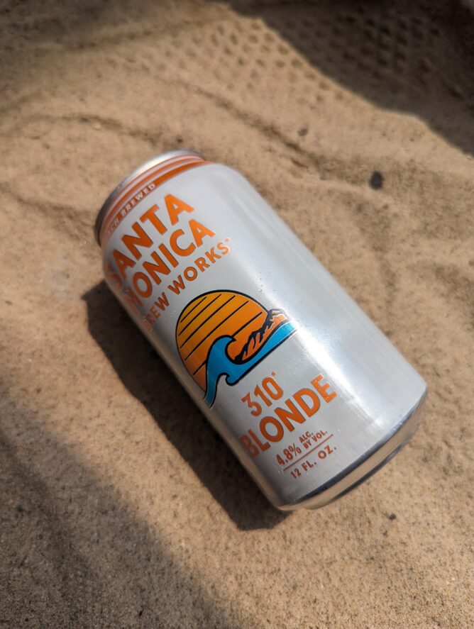 A can of Santa Monica Brew Works' 310 Blonde lying in the sand
